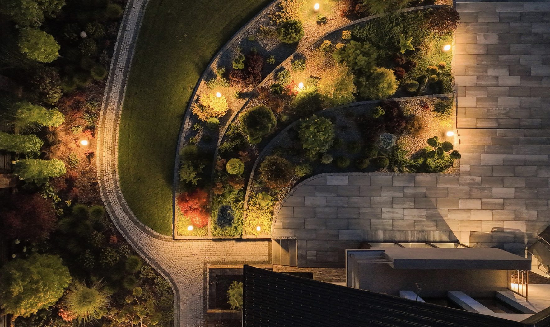 Warm landscape lighting reflecting off a modern water feature at night
